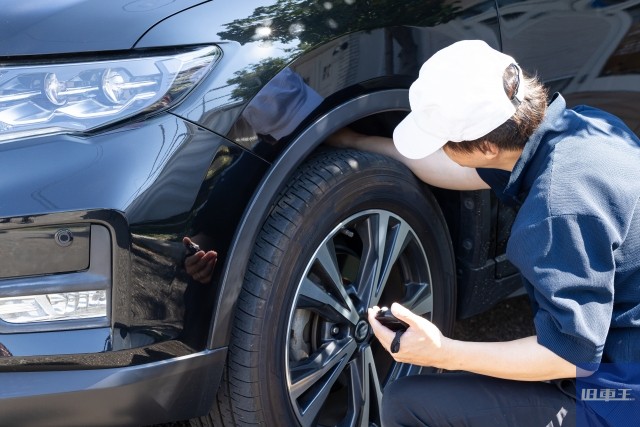 車の修理業者の男性がフロントタイヤを触っている